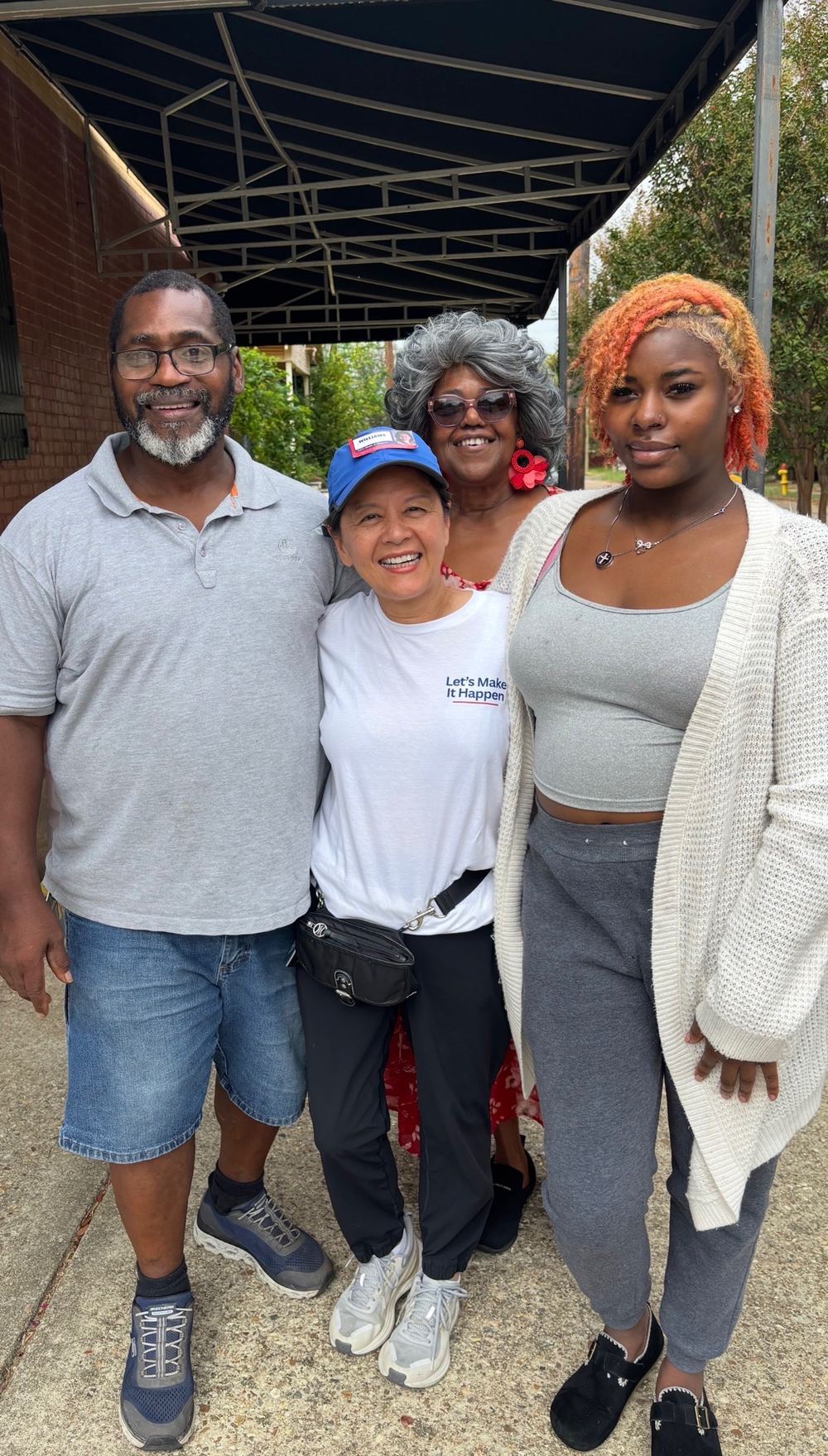Hanh Williams with three Allendale neighbors under a storefront awning while walking the neighborhood, October 3, 2026
