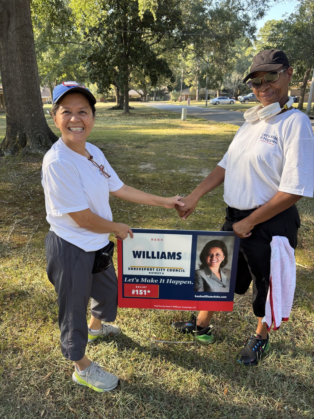 Hanh Williams shaking hands with a campaign volunteer beside a Hanh Williams yard sign in District A, September 29, 2026