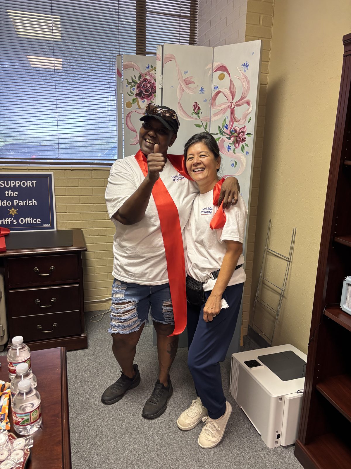 Hanh Williams giving a thumbs up with a campaign volunteer in a red sash at the District A campaign office, 1500 N Market St, October 2, 2026