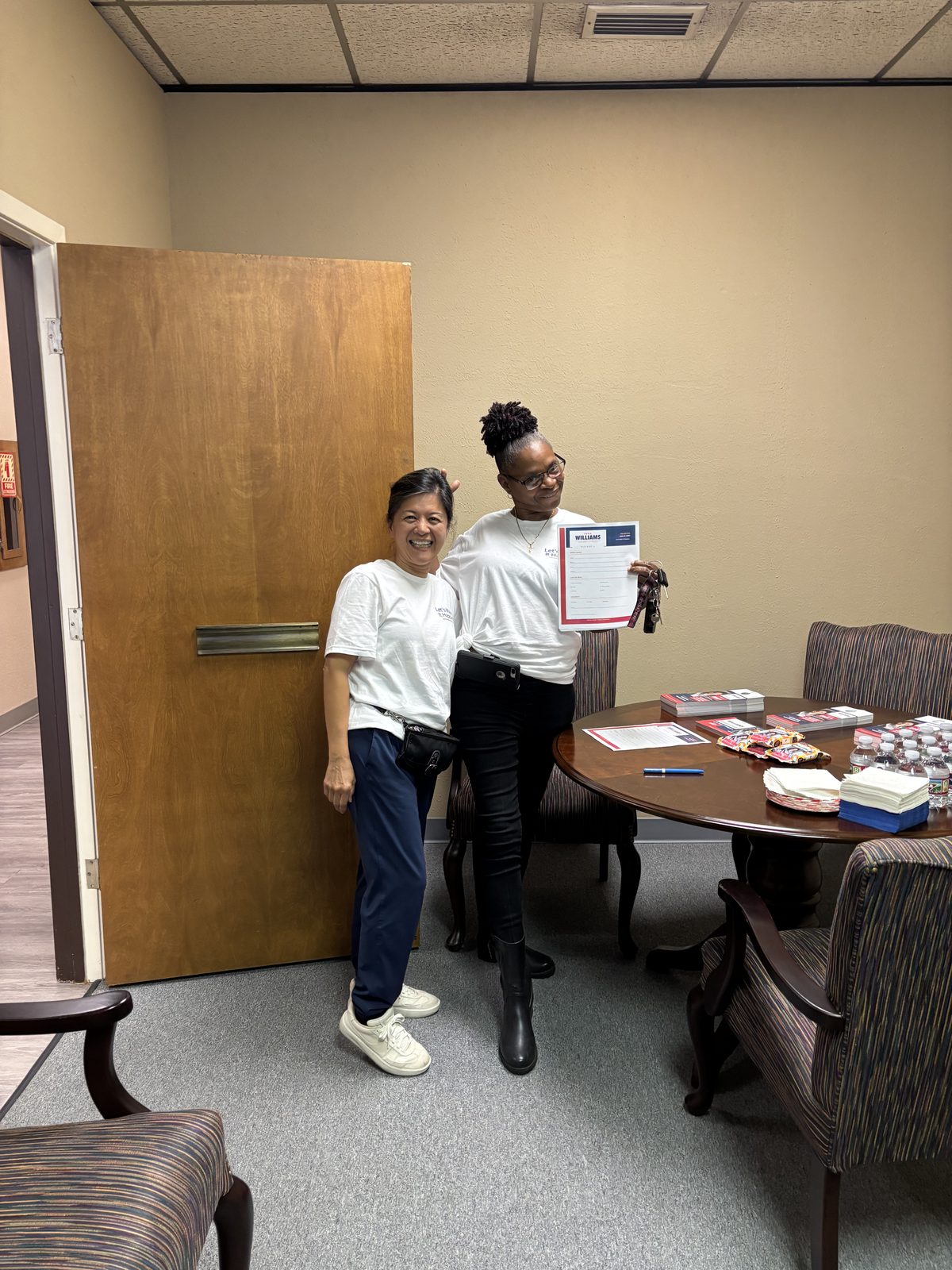 Hanh Williams with a campaign volunteer holding a sign-up form beside the push-card table at the District A campaign office, October 2, 2026