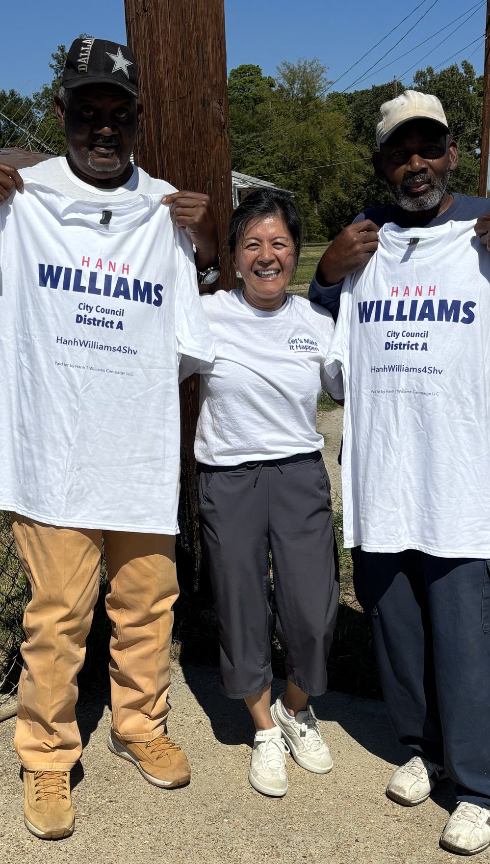 Hanh Williams smiling between two District A neighbors holding up white Hanh Williams City Council District A campaign shirts, October 7, 2026